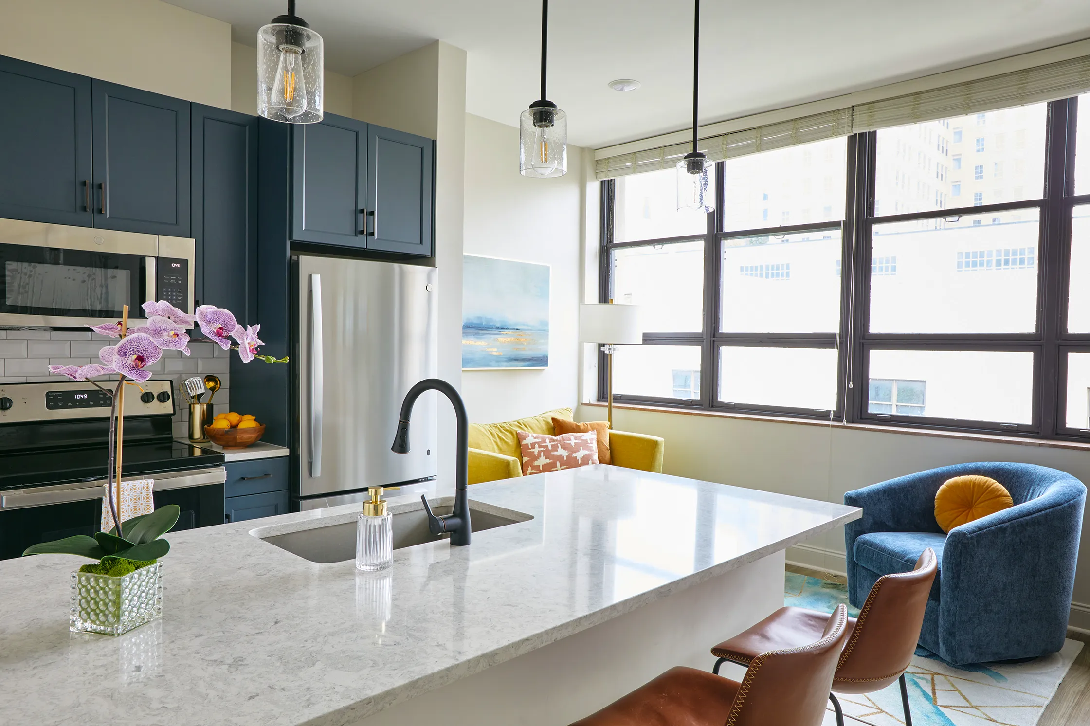 Modern kitchen at The Tribute Knoxville, TN, featuring large windows, sleek countertops, and stainless steel appliances, filled with natural light